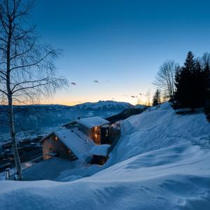 ein schneebedecktes Haus mit eingeschaltetem Licht in der Unterkunft nif: alpine taste in Levico Terme