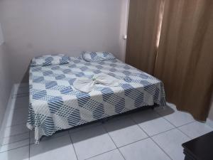 a bed with a blue and white comforter on it at Pousada Doce Lar in Itatiba