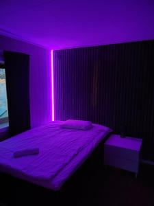 a bedroom with a bed with a purple lighting at Apartament 2 in Havøysund