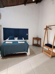 - une chambre avec un lit bleu et une chaise dans l'établissement La Bella Suítes, à Ilhabela