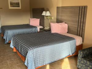 una habitación de hotel con 2 camas y una silla en Los Fresnos Inn and Suites, en Los Fresnos