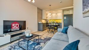 uma sala de estar com um sofá cinzento e uma televisão em Rezydencja Niechorze 213 - 5D Apartamenty em Niechorze