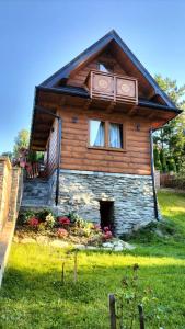 ein Holzhaus mit einem Fenster auf einem grünen Feld in der Unterkunft Chatka pod Lubaniem in Ochotnica Dolna