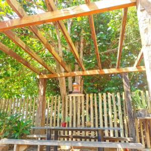 a wooden pergola with a bench under a tree at Mini Hotel Búzios in Búzios