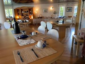 Aparthotel " Zur Müritz" في ريكلين: غرفة طعام مع طاولات خشبية وكراسي بيضاء