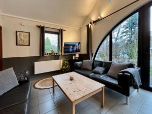 un soggiorno con divano nero e tavolo di Maison 25 a Houffalize