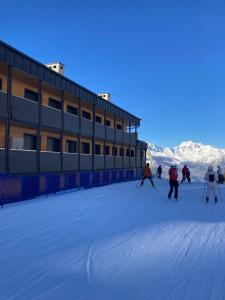 een groep mensen die skiën in de sneeuw voor een gebouw bij Sulle piste da Sergio&Lina in Pila