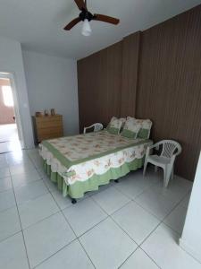 een slaapkamer met een bed met 2 stoelen en een plafondventilator bij Apartamento com VISTA MAR , no centro da Ilha de Guriri in São Mateus