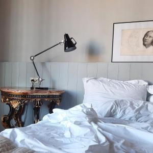 a bed with white sheets and a lamp on a table at Palazzo Capponi in Florence