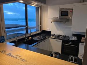a kitchen with a view of the ocean from a window at La Caravelle au plus près de la mer in Saint Malo