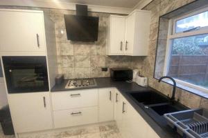 uma cozinha com armários brancos, um lavatório e uma janela em Spacious 3 Bed House London em Thornton Heath