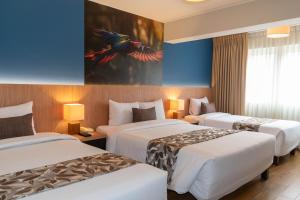una habitación de hotel con 3 camas y un cuadro en la pared en Hotel El Tambo 2, en Lima