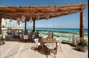 un patio con tavoli, sedie e vista sull'oceano di The Oceanfront by Casa Paraiso a Cancún