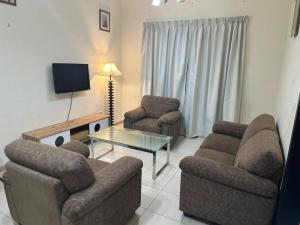 sala de estar con 2 sillas, mesa y TV en Stylish 1bhk at silicon oasis, en Dubái