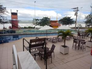 a patio with tables and chairs next to a pool at Studio pé na areia, vista, internet e ar in Macaé