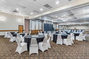 Seaport Inn & Suites في لويستون: قاعة اجتماعات مع طاولات وكراسي بيضاء