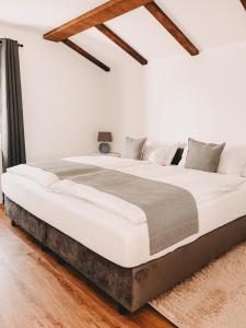 a large bed in a white room with wooden ceilings at Dorf 70 in Eichenberg