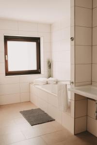 a white bathroom with a tub and a window at Dorf 70 in Eichenberg