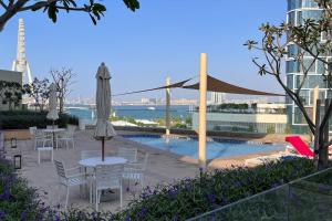 een patio met tafels en parasols en een zwembad bij Waves Holiday Homes - Sea View Luxury 3 Bedroom Apartment With Balcony in Dubai
