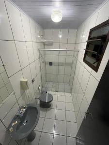 a white bathroom with a toilet and a sink at Free Way Motel in Poços de Caldas