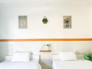 - 2 lits blancs dans une chambre ornée de fleurs sur le mur dans l'établissement HY. GUESTHOUSE PHU QUOC, à Duong Dong