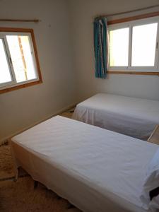 dwa łóżka w pokoju z dwoma oknami w obiekcie Gite Skoura w mieście Caïd Bou Malla