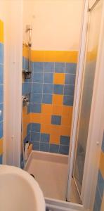 ein Bad mit einer Dusche mit blauen und gelben Fliesen in der Unterkunft Mesnil Val Plage in Criel-sur-Mer