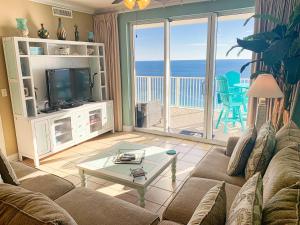 uma sala de estar com um sofá, uma televisão e uma varanda em Tropic Winds 2209 em Panama City Beach
