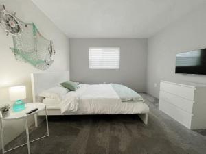 a white bedroom with a bed and a television at Beautiful Waterfront Beach Condo With Dock in St Pete Beach