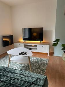 ein Wohnzimmer mit einem TV und einem weißen Tisch in der Unterkunft Cozy aux 3 frontières in Sierck-les-Bains