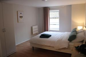 een witte slaapkamer met een bed en een raam bij Cozy aux 3 frontières in Sierck-les-Bains