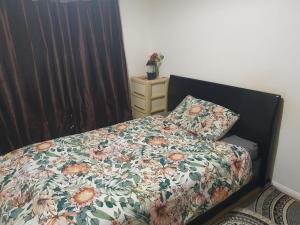 ein Bett mit einer Blumendecke und einem Kissen in der Unterkunft The Hidden Gem in Watford