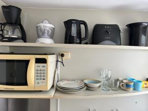 a microwave on a shelf with plates and cups at APARTAMENTO LA RURAL in Buenos Aires