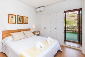 Schlafzimmer mit einem Bett mit weißer Bettwäsche und einem Fenster in der Unterkunft Queen of the ocean Villa: stately style house with pool in Málaga