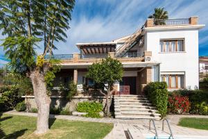 ein weißes Haus mit einem Baum davor in der Unterkunft Queen of the ocean Villa: stately style house with pool in Málaga