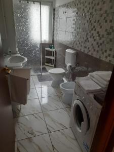 ein Badezimmer mit 2 WCs, einem Waschbecken und einer Waschmaschine in der Unterkunft Villa Azzurra in Monfalcone