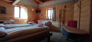 two beds in a room with wooden walls and windows at Baita Bertolini in Monclassico