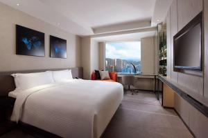 台北Humble House Taipei, Curio Collection by Hilton的配有床和电视的酒店房间