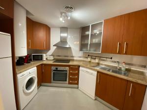 eine Küche mit Holzschränken, einer Waschmaschine und einem Trockner in der Unterkunft Apartamento Mar y Sol Benidorm in Cala de Finestrat