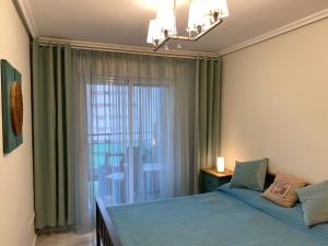 ein Schlafzimmer mit einem Bett und einem großen Fenster in der Unterkunft Apartamento Mar y Sol Benidorm in Cala de Finestrat