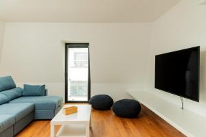 a living room with a blue couch and a tv at WelcomeBuddy - Casa Rua da Fonte in Ponta Delgada