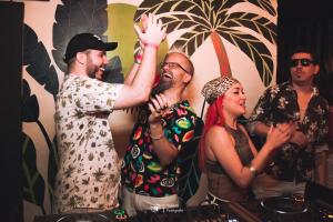 a group of people standing around a man raising his hand at El Misti Hostel Ipanema in Rio de Janeiro