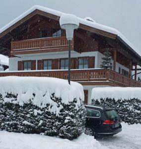 um carro estacionado em frente a uma casa coberta de neve em BIENE`S Ferientraum em Reit im Winkl