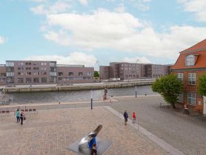 un gruppo di persone che camminano su un marciapiede di mattoni vicino a un fiume di Ohlerich Speicher App_ 04 a Wismar