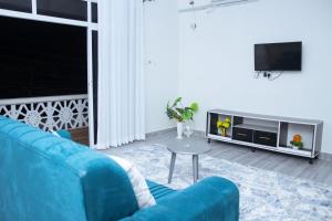 a living room with a blue couch and a tv at Kezmo Siloam Paradise in Mombasa