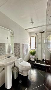 a white bathroom with a toilet and a sink at Allincay Cusco Apart Hotel in Cusco