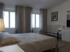 1 dormitorio con 1 cama, ventanas y TV en Lucca Old Town Apartment, en Lucca
