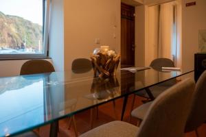 un tavolo di vetro con sedie e un vaso sopra di WelcomeBuddy - Villa Wave N'Sea - Beachfront a Mosteiros