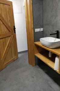 a bathroom with a white sink and a wooden door at Apartament NA PIĘTERKU in Rzepiska