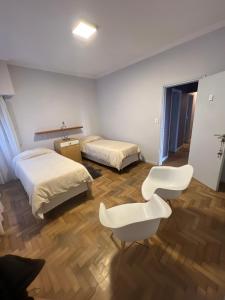 Zimmer mit 2 Betten und einem weißen Stuhl in der Unterkunft Habitaciones Garay 3100 in Mar del Plata
